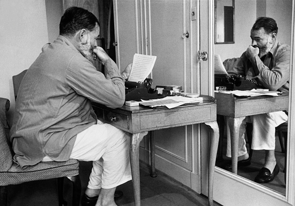 Hemingway seated in front of a typewriter